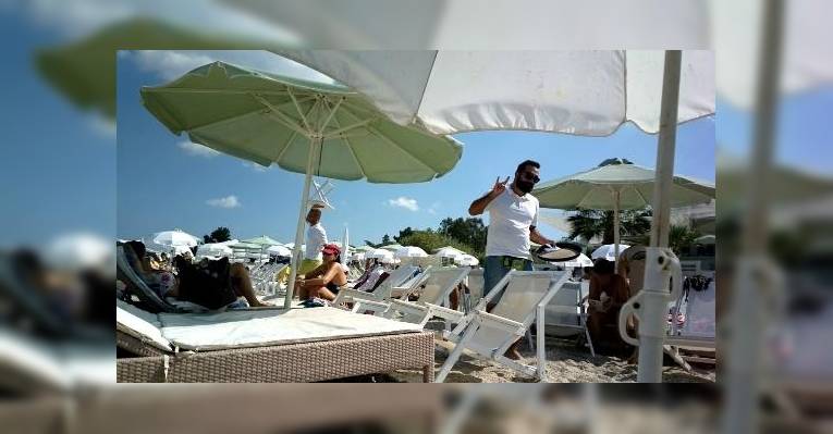 Официант Molos beach bar делает неприличный жест клиенту